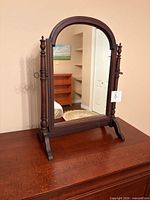 Full view of tabletop cheval mirror on wood surface
