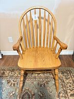 Front view of oak Windsor armchair showing bow back, spindles, saddle seat, turned arms and legs