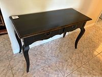 Front view of black solid wood console table with two drawers and cabriole legs