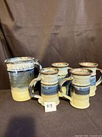 Pitcher and four matching stoneware mugs with blue and yellow glaze