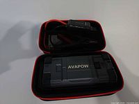 Jump starter inside open carrying case with jumper cables visible
