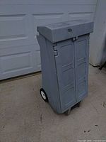 front view of gray plastic storage locker showing double doors and wheels