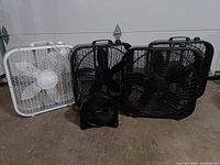 Group of five fans – one white box fan, three black box fans, one small black tabletop fan