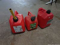 Front view of three red gasoline cans showing sizes, caps and spout
