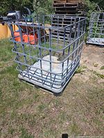 Full view of empty metal IBC cage on grass