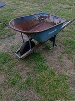 Full view of blue Jackson wheelbarrow showing rusted tray and overall structure