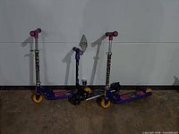 Three scooters standing upright against wall