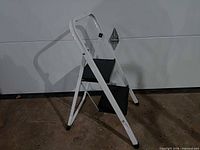 Full view of white metal two-step folding stool