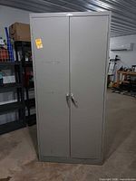 Front view of tall grey metal cabinet with two doors and handles