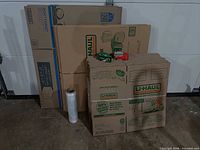 Stack of small, medium and large U-Haul boxes, tape rolls and stretch wrap displayed against garage wall