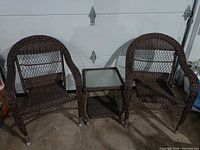 Full view of two resin wicker chairs and side table
