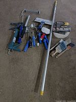 All items laid out showing variety of painting tools including extension pole, caulking guns, roller frames and brushes