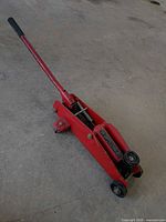 Full view of red hydraulic floor jack with handle extended