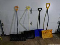 Five shovels leaning on garage door, shows overall lot