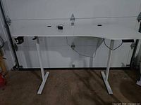 Full view of white motorized standing desk with dual legs and grommets