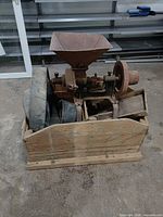 Overall view of cast iron grain grinder with hopper and wooden base