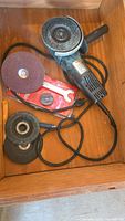 Angle grinder, four loose discs and spanner laid in drawer