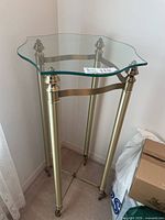 Full view of brass and glass tall side table in corner