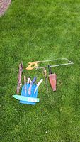 All items laid out on grass: saws, knives, steel, scabbard, belt