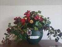 Front view of green ceramic pot with artificial Christmas floral arrangement