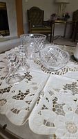 Round cut crystal bowl, oval dish, two candlesticks on lace cloth