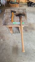 Long double-bit axe and smaller hatchet on a wooden stool