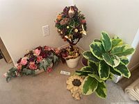 Overall lot showing three floral arrangements, empty planter and sunflower wall piece
