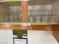 Twelve clear stemmed wine glasses with pinwheel cut on cabinet shelf