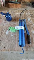 Blue lever grease gun and blue oil can on workbench