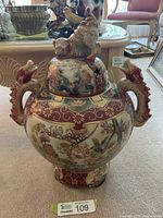 Full view of urn with lid and base showing cat finial and dragon handles