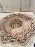 Full view of octagonal wool rug showing shape, fringe and floral border