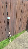 Full view of assembled 10ft rod with reel attached leaning against fence