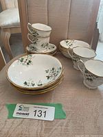 Stacked teacups, saucers and bowls showing pattern and gold rims