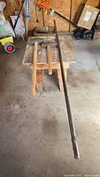 Two sledge hammers on table with long steel rod