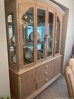 Full view of two-piece light wood china cabinet with glass doors and arched crown