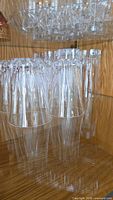 Large and small clear glass tumblers arranged upside-down in cabinet
