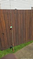 Full view of assembled rod and reel leaning against fence