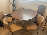 Round wood-grain table with four matching chairs positioned around it
