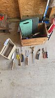 Overview of crate, kneeler and lined-up hand tools on floor