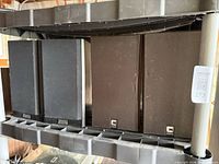 Four speakers on shelf: two black Recoton wireless and two brown Celestion DL4