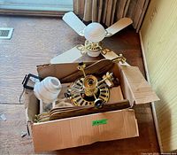 Box with disassembled ceiling fan motor, blades, globes and hardware