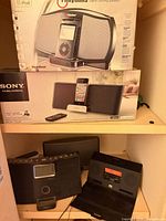 Shelf view showing boxed iRhythms and Sony docking speakers plus loose Bose/TEAC/Altec units