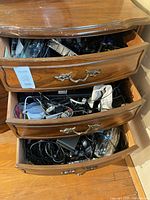 Three dresser drawers filled with assorted cables and small electronic accessories