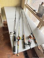 Four fishing rods with reels laid on table