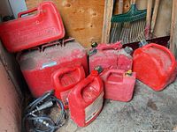 Group of red fuel containers and hose in shed