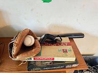 Stacked board games with glove, ball and bat visible