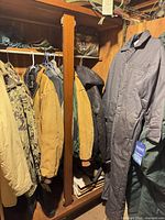 Closet view showing camouflage, tan, green, black jackets and grey coveralls