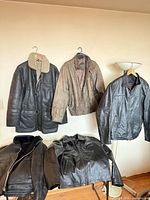 Group shot of all five leather outerwear items hanging and laid out
