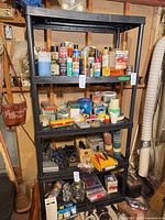 Full view of black plastic four-tier shelving unit with contents
