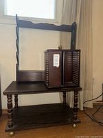 Overall view of wooden rolling table, spinning CD tower, and pool cue rack